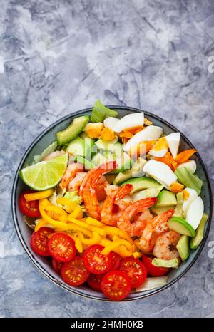 Deliziosa insalata fresca con gamberi, avocado, uova, peperone, pomodori ed erbe Foto Stock