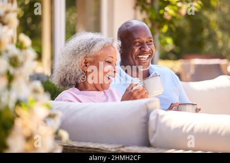 Coppia in pensione seduta all'aperto a casa avendo caffè del mattino insieme Foto Stock