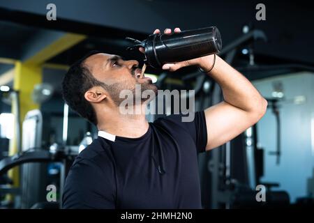 bodybuilder bere o prendere proteine in polvere e mescolando con acqua in bottiglia scuotendo in palestra - concpet di guadagno muscolare, fitness e. Foto Stock