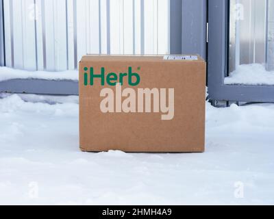 Tambov, Federazione russa - 05 febbraio 2022 iHerb cartone consegnato ad un cancello casa. Consegna in inverno. Foto Stock