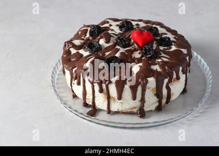 Torta di profiterole decorata con cioccolato e prugne su un piatto su sfondo grigio Foto Stock