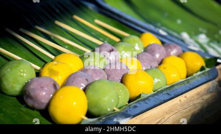 Dolci a base di farina verde, viola, gialla, spiedini disposti su foglie di banana verde, dolci tradizionali di popolazioni indigene. Foto Stock