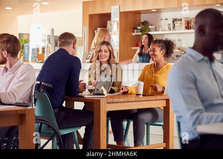 Gruppo di colleghi d'affari che hanno riunione informale intorno al tavolo in Office Coffee Shop Foto Stock