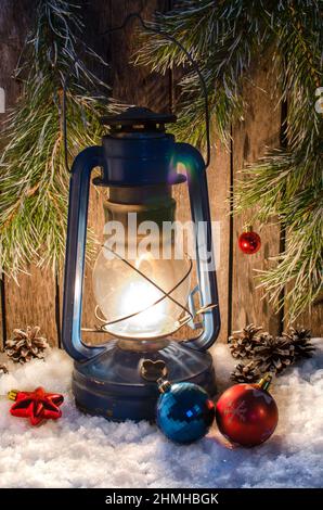 Lampada di kerosene sul bianco della neve luci decorazioni di Natale e fir ramo su uno sfondo di legno Foto Stock