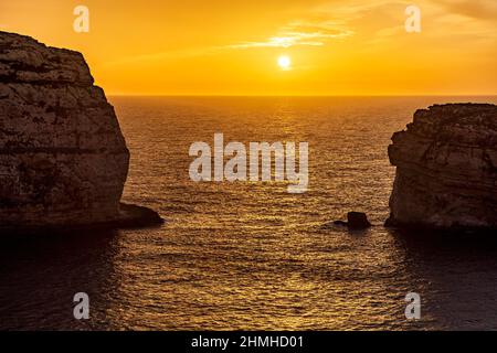 Il sole tramonta in colori gloriosi sulla Baia di Dwejra a Gozo Foto Stock