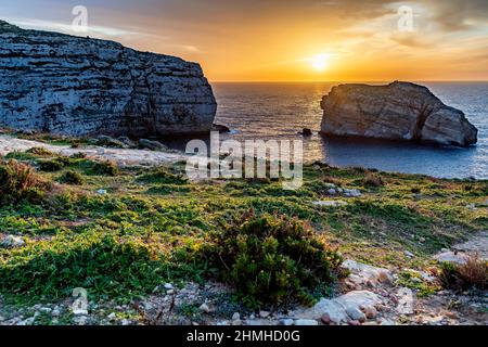 Il sole tramonta in colori gloriosi sulla Baia di Dwejra a Gozo Foto Stock