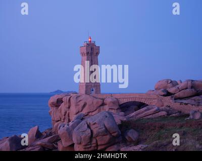 Phare de Ploumanac'h al tramonto sulla Côte de Granit Rose nel dipartimento della Côtes d'Armor della Bretagna. Il faro è stato costruito dal granito rosa della costa rocciosa e si fonde armoniosamente con i dintorni Foto Stock