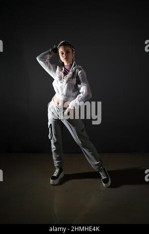 Immagine verticale di una giovane donna con stile urbano in piedi e in posa in studio. Foto Stock