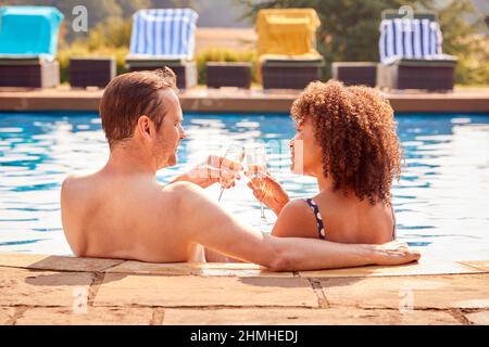 Coppia romantica che beve Champagne in piscina in vacanza Foto Stock