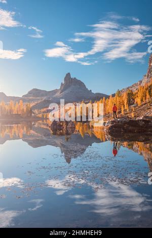 Italia, Veneto, Belluno, Cortina d'Ampezzo, Rifugio Croda da Lago, uomo (45 a 50 anni) che si erge su una roccia al lago Federa in autunno, Foto Stock