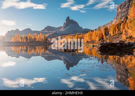 Italia, Veneto, Belluno, Cortina d'Ampezzo, Rifugio Croda da Lago, uomo (45 a 50 anni) che si erge su una roccia al lago Federa in autunno, Foto Stock