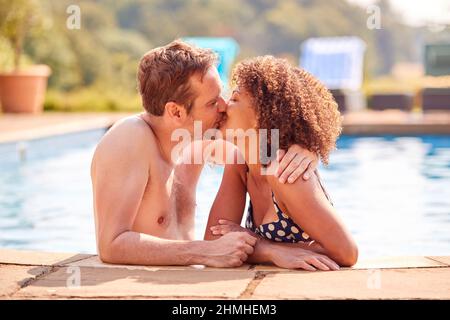 Coppia romantica baciare in piscina in vacanza Foto Stock