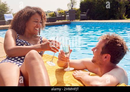 Coppia romantica che fa brindisi con champagne in piscina in vacanza Foto Stock