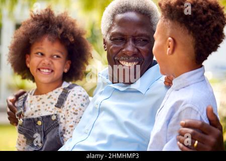 Nonno amorevole che parla con i nipoti in Garden at Home Foto Stock