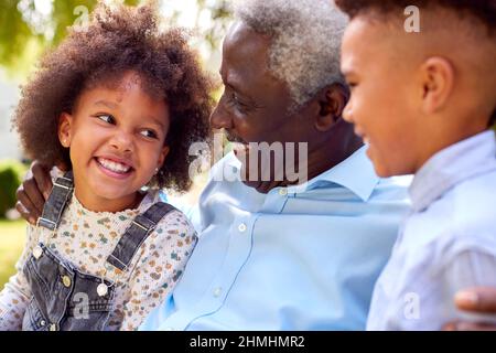 Nonno amorevole che parla con i nipoti in Garden at Home Foto Stock