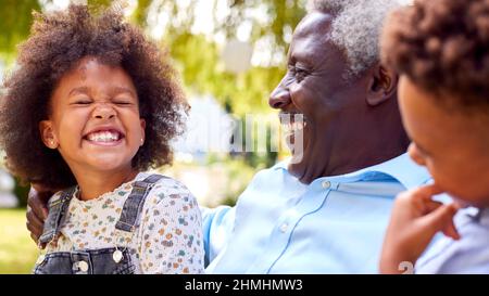 Nonno amorevole che parla con i nipoti in Garden at Home Foto Stock