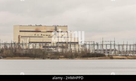 Vecchia centrale elettrica e termica combinata centrale industriale con linee elettriche ad alta tensione vicino all'acqua del lago. Foto Stock