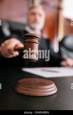 fuoco selettivo di gavel in legno in mano a giudice sfocato in tribunale Foto Stock