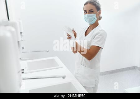 Ritratto di medico femminile o infermiere asciugando le mani con il tessuto di carta in ospedale dopo il lavaggio delle mani. Igiene, assistenza sanitaria. Foto Stock