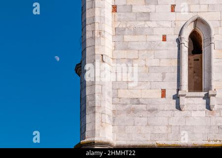 Un particolare del campanile della chiesa di San Lorenzo Martire, Orentano, Pisa, Italia, con sullo sfondo la luna crescente Foto Stock