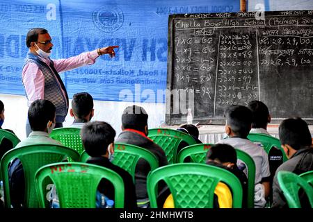 Kolkata, India. 10th Feb 2022. Un insegnante ha visto insegnare gli studenti durante una lezione all'aperto. Il governo del Bengala occidentale ha dato il permesso di tenere classi a cielo aperto per gli studenti di classe VII (sette) e inferiore dalla settimana corrente in poi, dopo due anni di restrizioni del codice-19. Credit: SOPA Images Limited/Alamy Live News Foto Stock