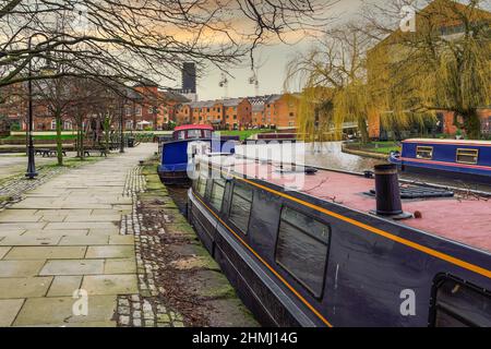 Manchester, Regno Unito ormeggiate barche strette nella zona di Castlefield Basin. Case galleggianti sul canale Bridgewater, prima dei tradizionali edifici bassi. Foto Stock