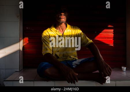 Un operaio afro-colombiano beve un piccolo “tinto” (caffè nero) mentre si riposa all’ombra sul mercato di Bazurto a Cartagena, Colombia. Foto Stock