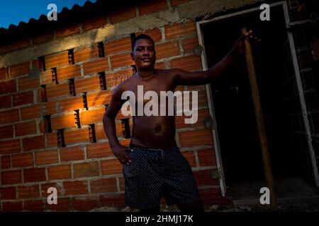 Un uomo afro-colombiano pone per una foto mentre costruisce la sua casa in Olaya Herrera, un quartiere di classe sociale bassa a Cartagena, Colombia. Foto Stock