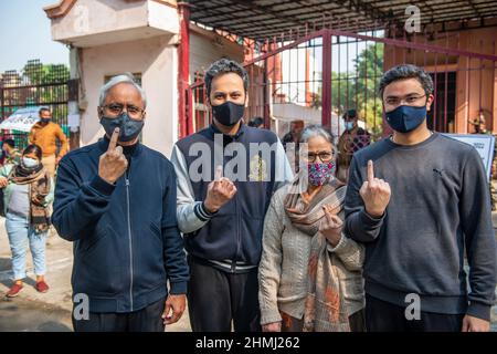 Ghaziabad, India. 10th Feb 2022. I membri della famiglia hanno visto mostrare le loro dita inchinate dopo aver castrato le loro urne in un seggio elettorale nella città di Ghaziabad durante la prima fase delle elezioni dell'assemblea di stato di Uttar Pradesh. Credit: SOPA Images Limited/Alamy Live News Foto Stock