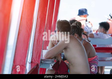 Vista posteriore dei passeggeri amanti che si rilassano sul balcone godendo la vista dalla barca dell'isola di Samui nel mare. Felice coppia di turisti casual fuori su tropicale Foto Stock