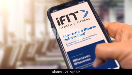 New York, USA, settembre 2021: Tenere un telefono con l'app mobile ifit sullo schermo con una palestra sfocata sullo sfondo durante il giorno. Ifit i Foto Stock