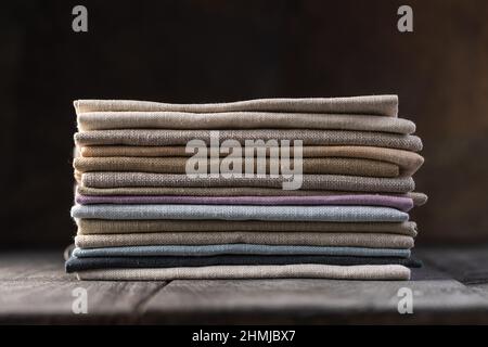 Un mucchio di quattro tessuti di lino naturale ripiegati e colorati ecologicamente compatibili su sfondo rustico Foto Stock