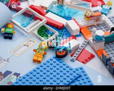 Tambov, Federazione Russa - 09 febbraio 2022 alcuni pezzi Lego e minifigure su una scrivania con un libretto di istruzioni aperto vicino a loro. Primo piano. Foto Stock