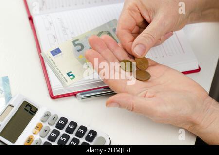 Il pensionato sta calcolando il profitto. Depositi pensionistici. Centesimi di Euro in vecchie mani femminili. Foto Stock