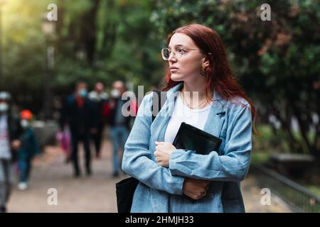 Attraente giovane donna d'affari che indossa abito blu con tablet digitale all'aperto, architetto professionista a piedi al parco Foto Stock