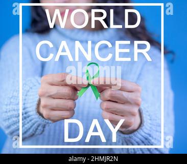 Nastro verde per supportare la consapevolezza del cancro del fegato e surrenale, mani umane che tengono nastro verde. Giornata mondiale del cancro. Testo con la leggenda: 'Cancro del mondo da Foto Stock