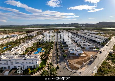 Edifici residenziali di recente costruzione, moderni e high-tech con piscina e strade vuote fiancheggiate da palme, punto di vista del drone. Immobiliare, sviluppo urbano. Foto Stock