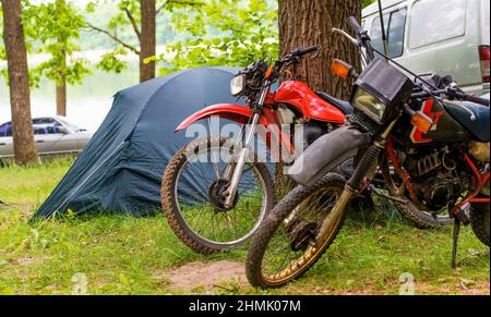 Picnic sulle motociclette. Le motociclette sono vicino alla tenda durante il pic-nic sul lago. Foto Stock