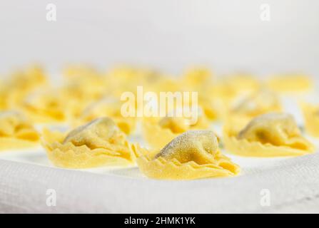 Tortellini italiani su tela bianca, paste ripiene non cotte Foto Stock