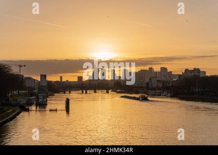 Banchine della Senna. Vista del trasporto di una chiatta che naviga lungo la Senna e il quartiere della Difesa al tramonto da Clichy Bridge Foto Stock