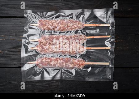 Kebab confezionato da agnello o set di carne di montone, su sfondo tavolo di legno nero, vista dall'alto piatto Foto Stock