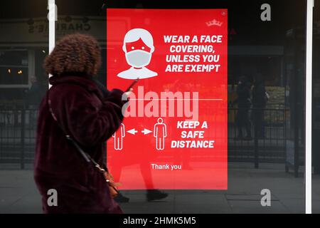 Londra, Regno Unito. 10th Feb 2022. Una donna guarda un poster "indossare una copertura facciale a meno che non si è esenti" visualizzato in una vetrina di negozio.il primo ministro, Boris Johnson ha annunciato che presenterà il piano del governo per vivere con Covid-19 quando il Parlamento ritorna da una breve recinione il 21 febbraio, Con tutte le restrizioni di Covid-19 da scartare. Credit: SOPA Images Limited/Alamy Live News Foto Stock