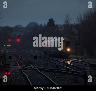 London midland Bombardier treno classe 172 con i suoi fari che illuminano la pista e segnali rossi al raccordo di Stourbridge in una notte bagnata e buia Foto Stock