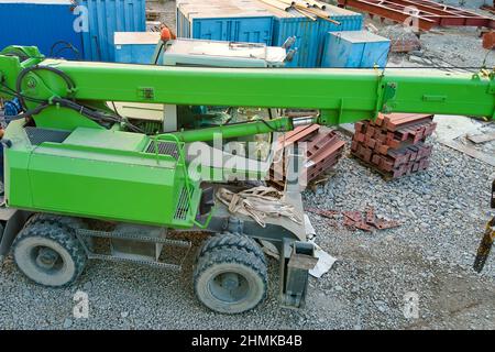 Sollevamento del trattore a gru in cantiere industriale. Macchinari per impieghi pesanti per l'edilizia. Foto Stock