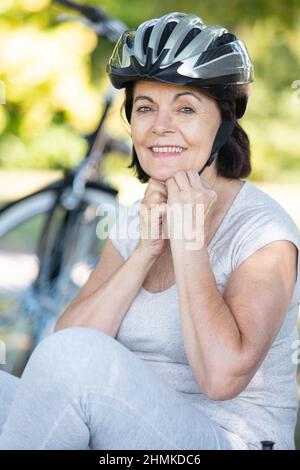 ritratto di donna ciclista matura indossando casco protettivo Foto Stock