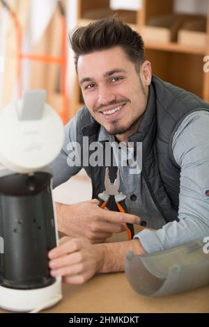 Tuttofare nel lavoro di riparazione complessiva macchina da caffè in cucina Foto Stock