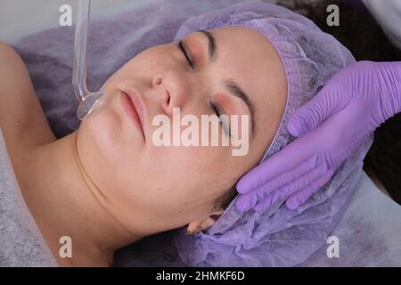 Il cosmetologo fa una procedura di peeling all'acqua per il cliente in salone di bellezza. Vista laterale. Il concetto di cura professionale della pelle. Foto Stock