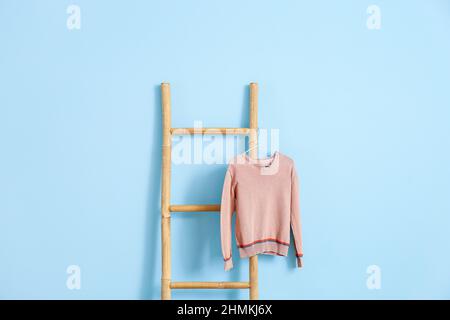 Ripiano scala e maglione in maglia su sfondo blu Foto Stock