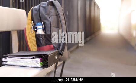 Uno zaino completo per gli studenti completo di bottiglia d'acqua su un sedile a panca con un raccoglitore ad anelli organizzato pieno di libri e note della scuola. Scuola superiore e. Foto Stock