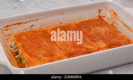 Assemblare le lasagne. Condimento dell'ultimo strato di lasagna con salsa di marinara. Ricetta per lasagne di spinaci Foto Stock